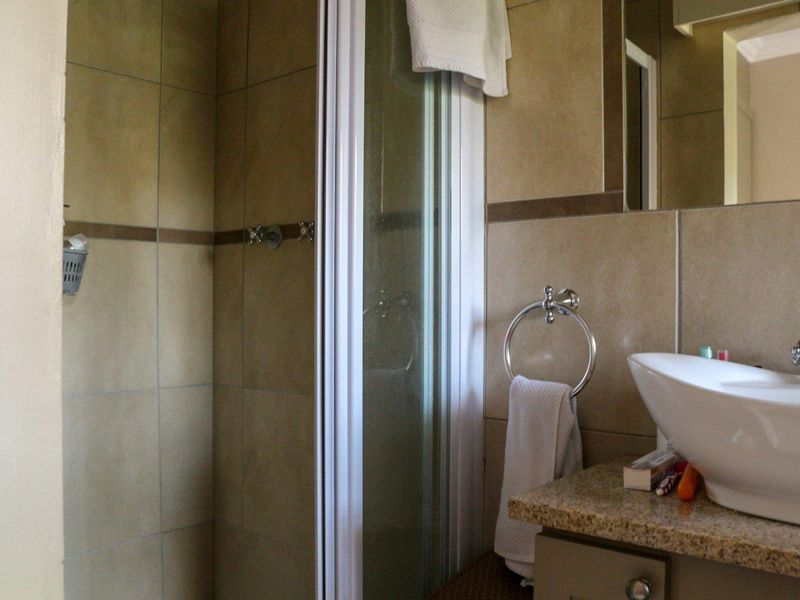 A functional bathroom featuring a tiled shower enclosure, a granite-topped vanity with a vessel sink, and wall-mounted fixtures.