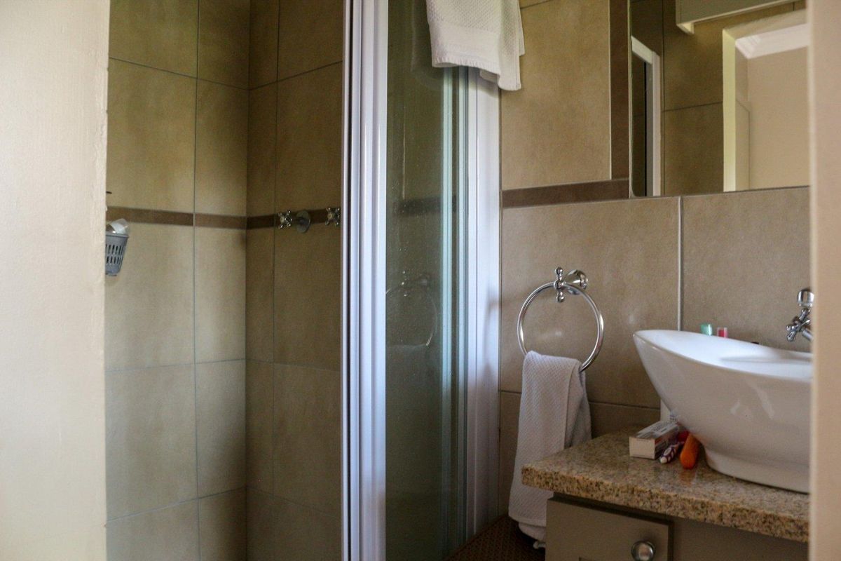 A functional bathroom featuring a tiled shower enclosure, a granite-topped vanity with a vessel sink, and wall-mounted fixtures.