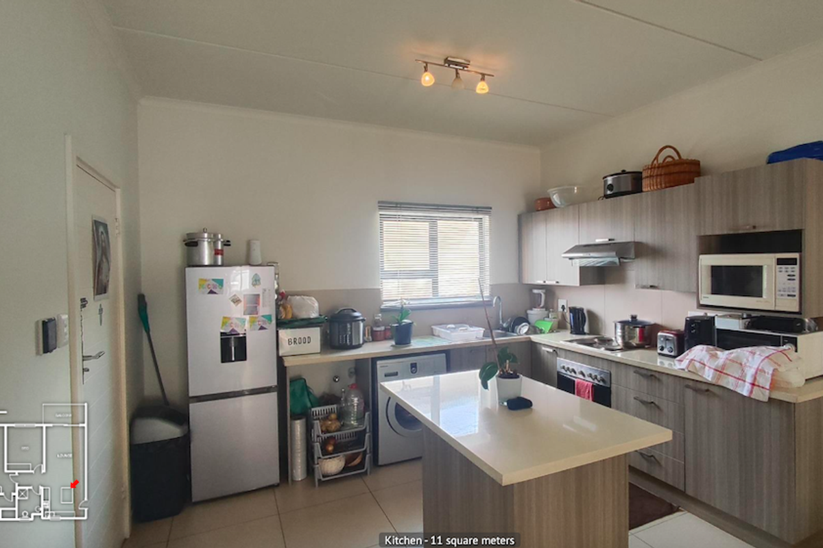 A functional kitchen featuring modern wood-finish cabinetry, stone countertops, a central island, and integrated appliances, providing a practical workspace.