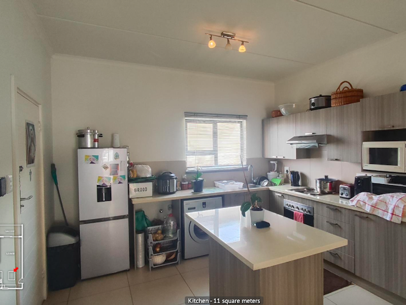 A functional kitchen featuring modern wood-finish cabinetry, stone countertops, a central island, and integrated appliances, providing a practical workspace.