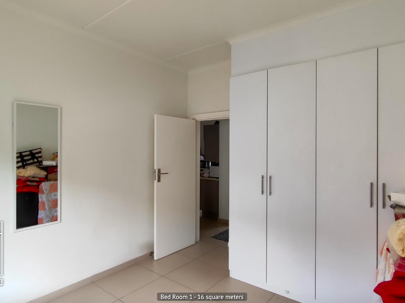 A spacious bedroom featuring neutral tiled flooring and extensive built-in cupboard storage, offering a clean and functional living space.