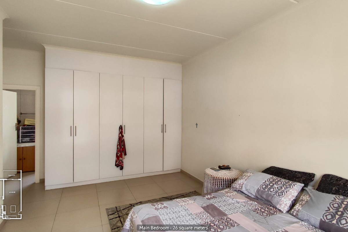 Spacious main bedroom featuring neutral tiled flooring and extensive built-in cupboard storage.