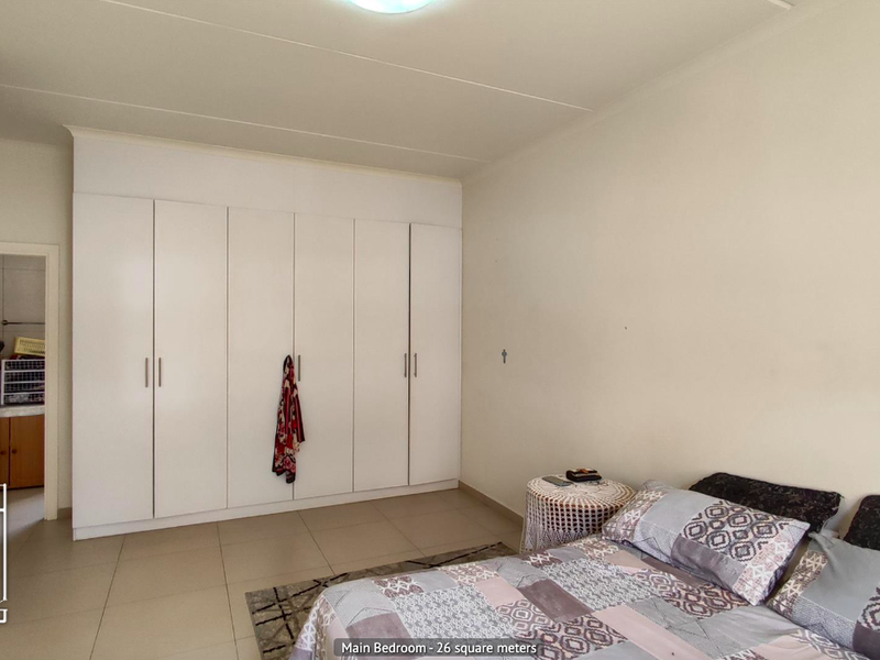 Spacious main bedroom featuring neutral tiled flooring and extensive built-in cupboard storage.
