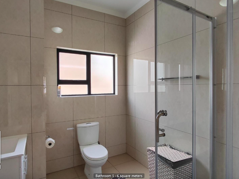 Modern bathroom featuring floor-to-ceiling neutral tiling, a glass-enclosed shower, a vanity unit, and a toilet.