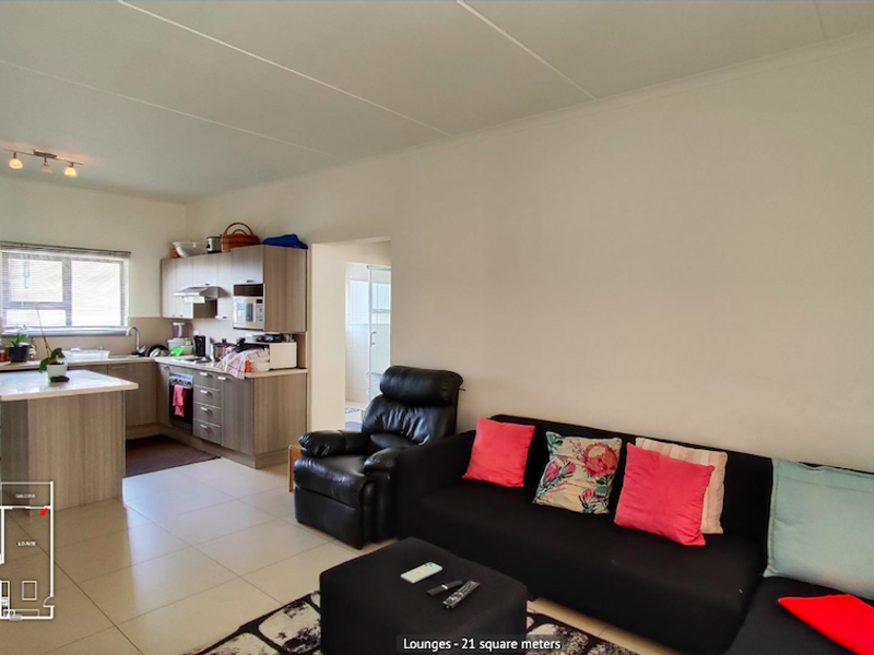Open-plan living area featuring a functional kitchen with built-in cabinetry, an island, and tiled flooring throughout.