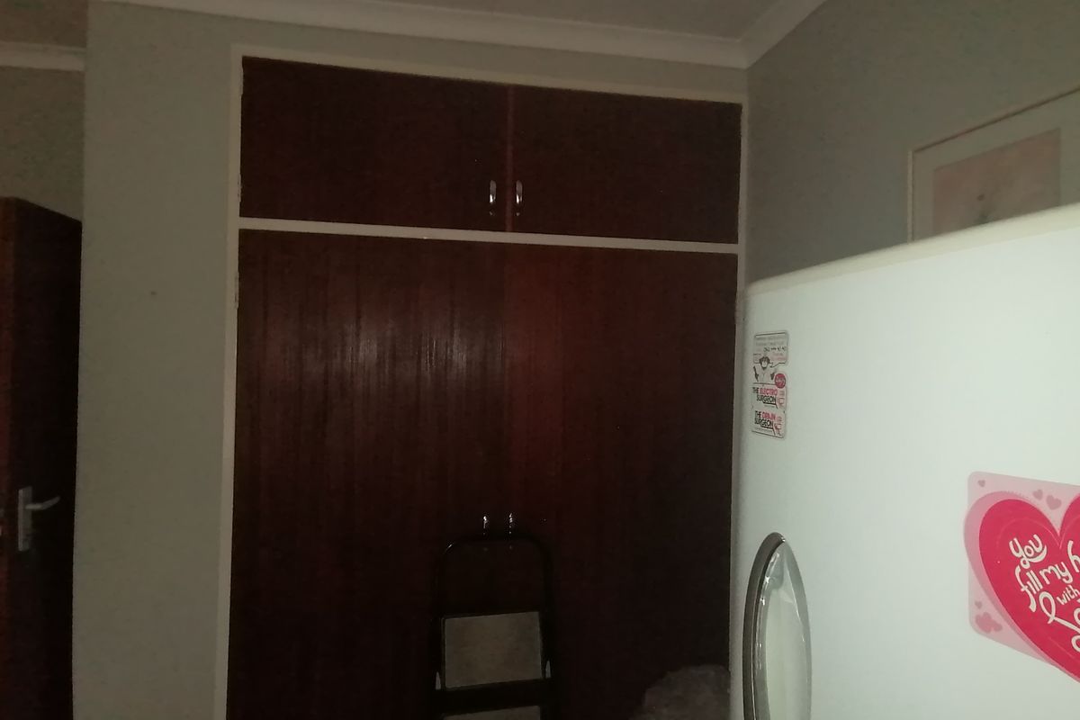 A bedroom interior featuring built-in wooden cupboards with overhead storage compartments.
