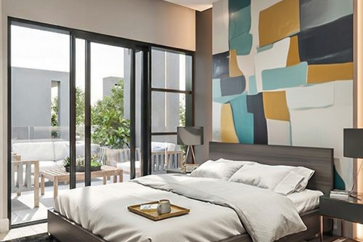 Modern bedroom featuring large sliding glass doors that open onto a private balcony, providing ample natural light and a seamless indoor-outdoor flow.