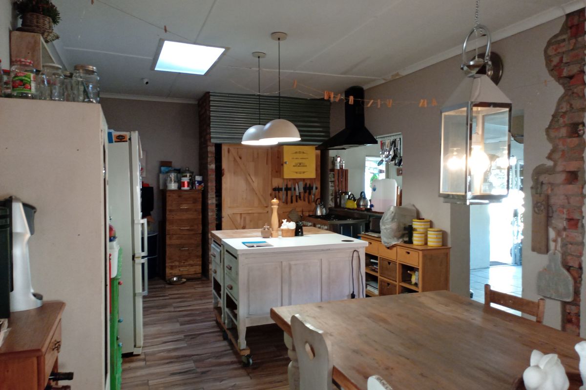 A rustic-style kitchen featuring a central island, exposed brick accents, a skylight, and pendant lighting, offering a unique character-filled cooking and dining space.