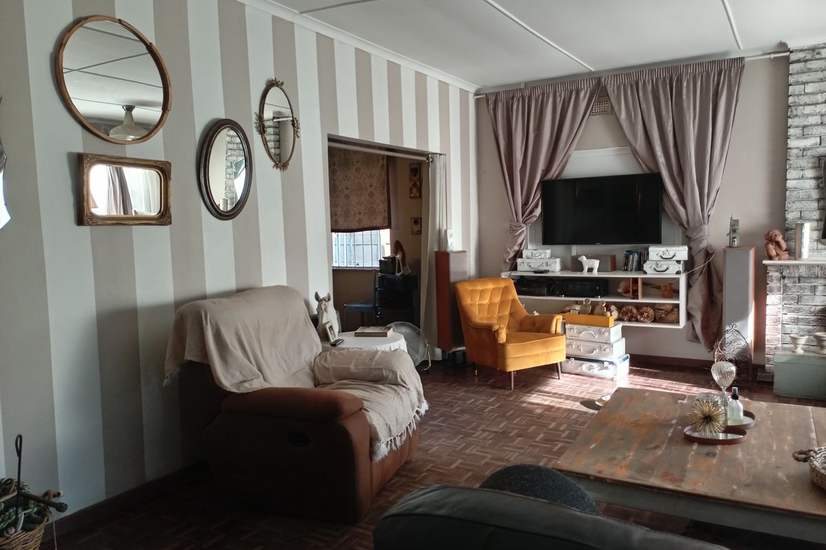 A living room featuring classic parquet flooring, a brick fireplace, and built-in shelving, offering a cozy and traditional atmosphere.