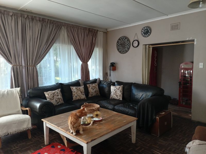 A spacious living room featuring large windows with curtains and a neutral wall finish, offering a comfortable area for relaxation.
