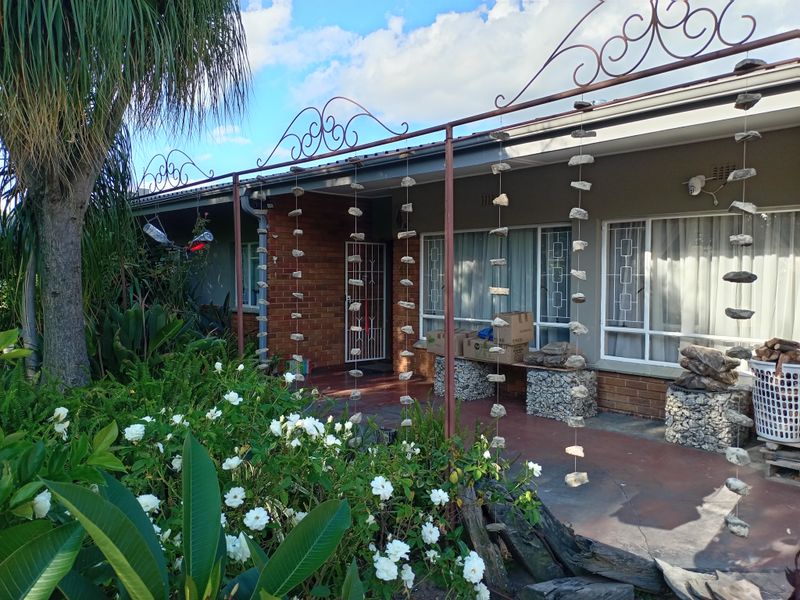 A covered patio area featuring a metal pergola frame, brick exterior wall, and security features, offering a functional outdoor space for relaxation.