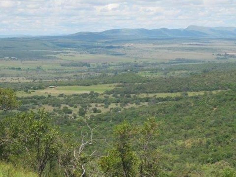A scenic, elevated landscape view overlooking expansive natural bushveld and rolling hills, showcasing the property's surrounding environment.