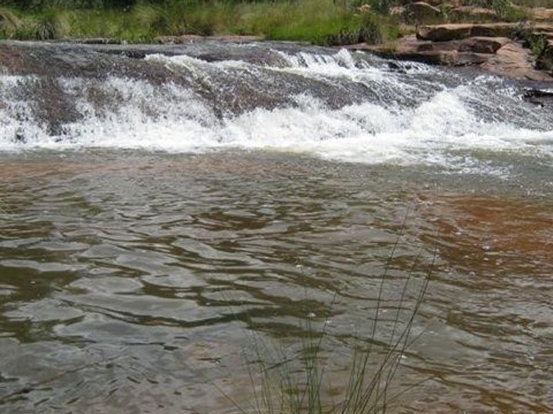 A scenic view of a natural waterfall flowing over a rocky riverbed on the property.