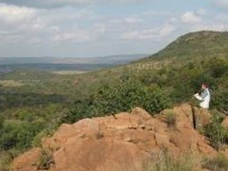 A scenic elevated view overlooking a vast natural landscape with rocky terrain and native vegetation.