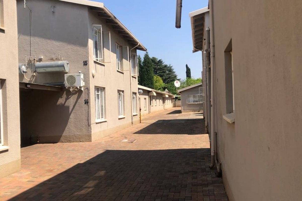A view of the exterior walkway between apartment blocks, featuring paved ground and multi-story residential building facades.