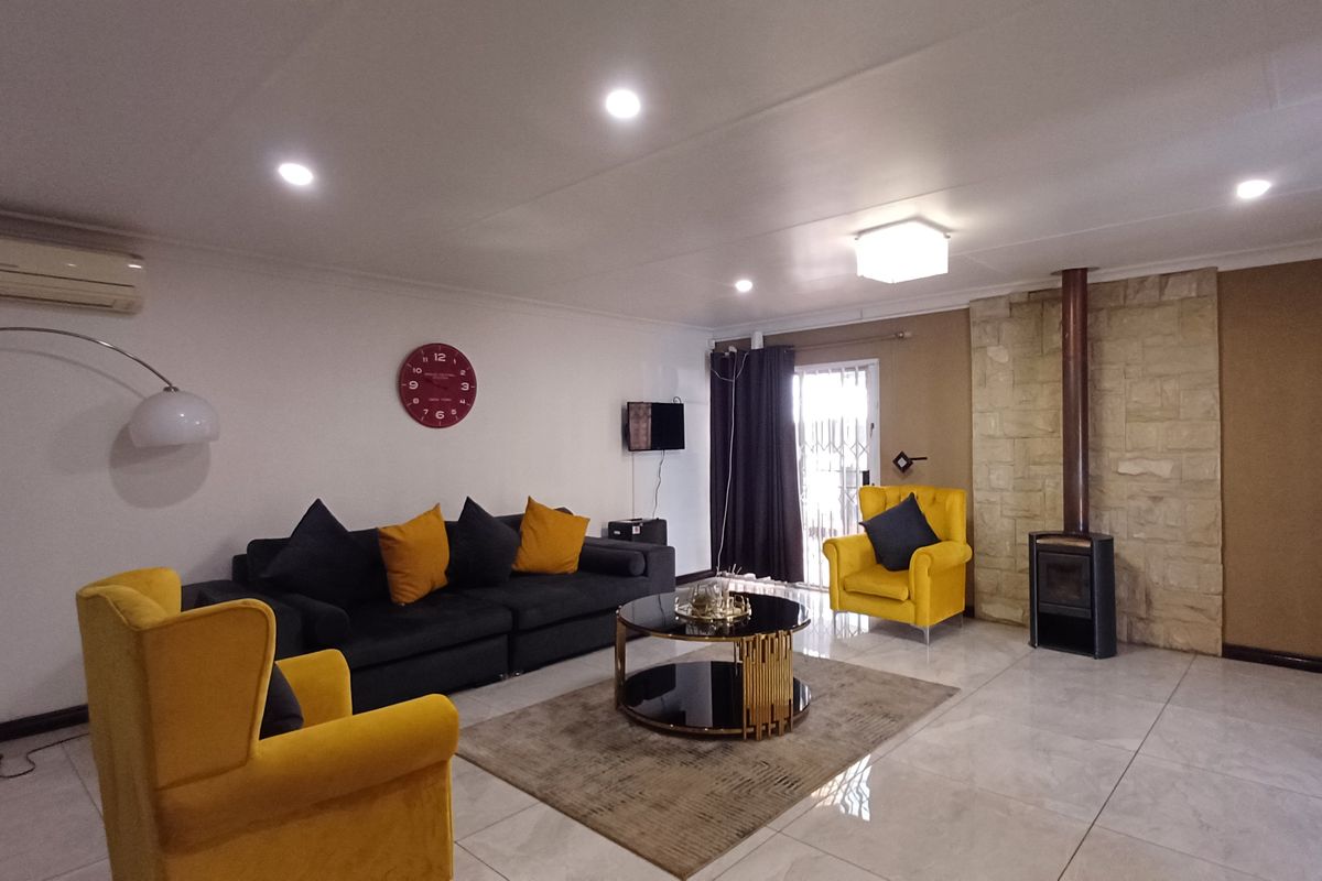 Spacious living room featuring tiled flooring, a stone-clad fireplace with a wood-burning stove, and recessed lighting, creating a comfortable and inviting atmosphere.