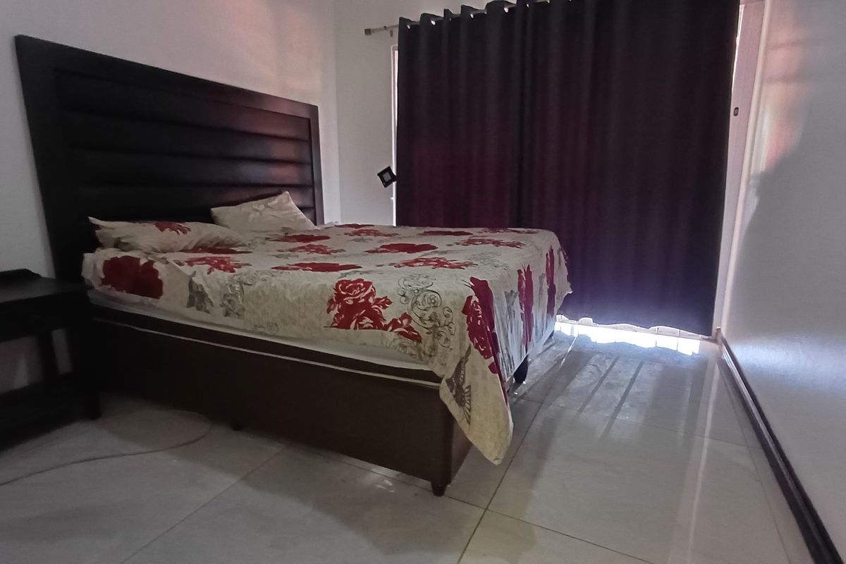 A bedroom featuring tiled flooring and floor-to-ceiling curtains, providing a functional space with neutral wall finishes.