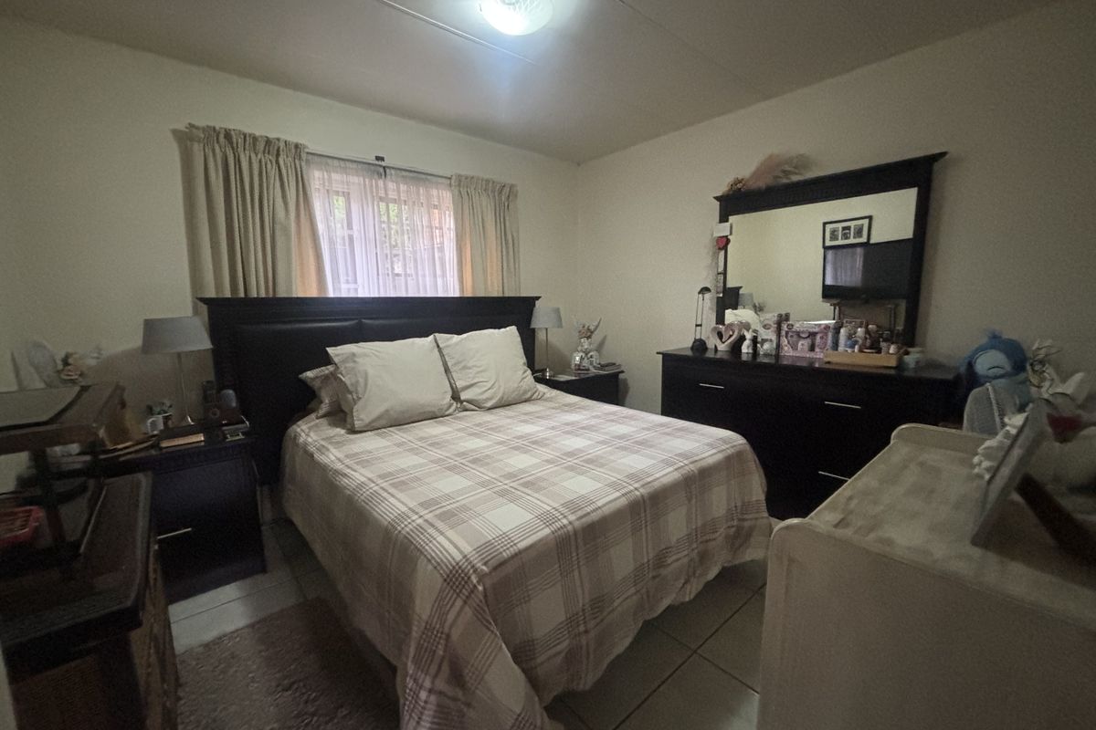 A standard bedroom featuring tiled flooring and neutral wall finishes, providing a functional space with natural light from the window.