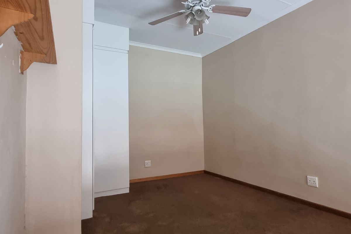 An empty bedroom featuring built-in cupboards, a ceiling fan, and carpeted flooring, ready for personalization.