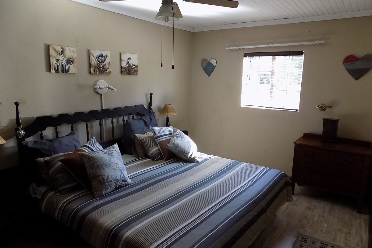 A cozy bedroom featuring a beadboard ceiling, ceiling fan, and timber-look flooring, providing a comfortable and functional sleeping space.