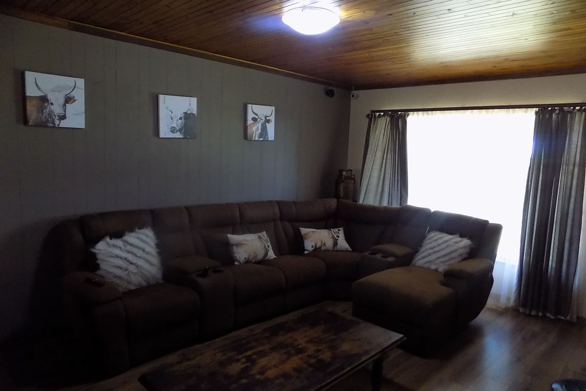 A living room featuring a timber-clad ceiling and laminate flooring, providing a warm and traditional aesthetic.