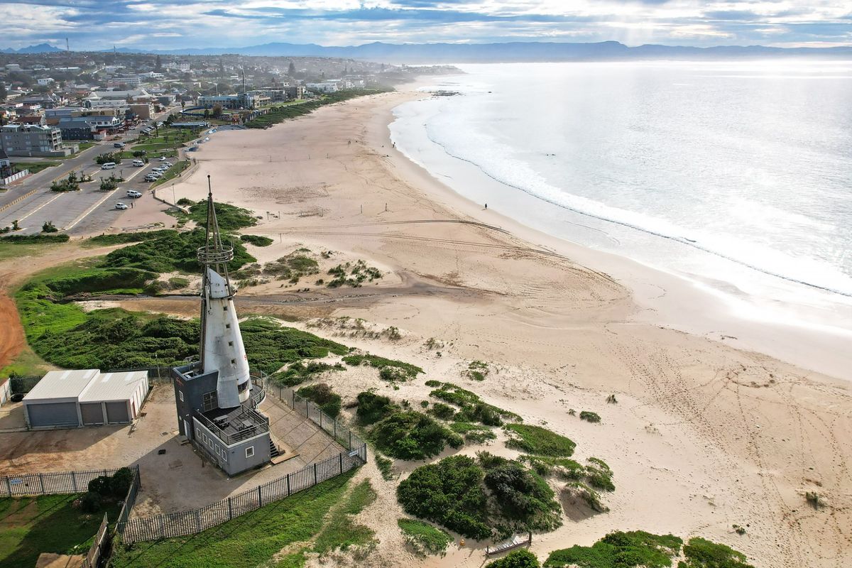 Aerial view of a coastal property featuring a lighthouse structure situated directly adjacent to the beach and oceanfront.