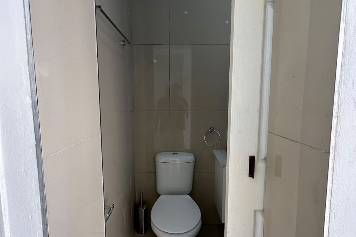 A compact, tiled bathroom featuring a modern toilet and vanity unit, presented in a clean and functional condition.