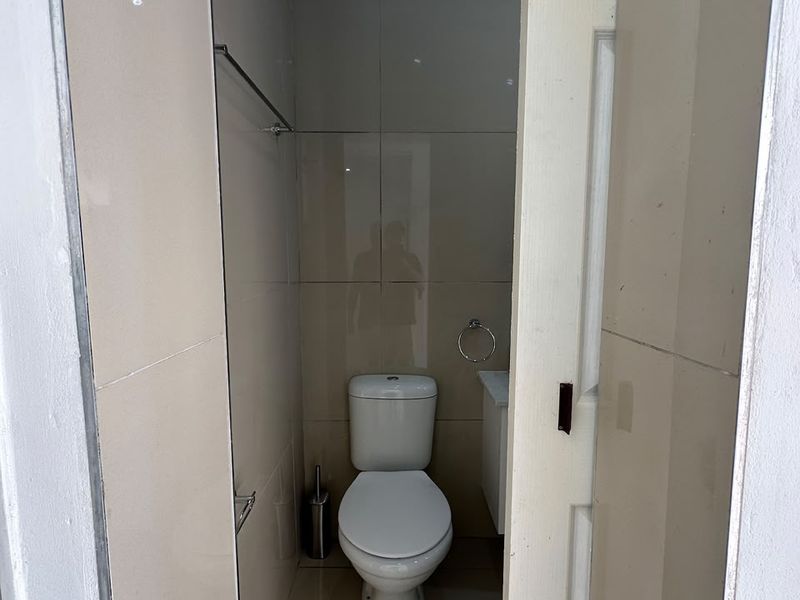 A compact, tiled bathroom featuring a modern toilet and vanity unit, presented in a clean and functional condition.