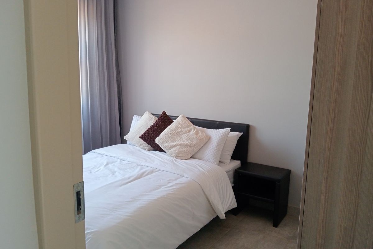 A well-maintained bedroom featuring neutral tiled flooring and a built-in wardrobe, offering a clean and functional living space.