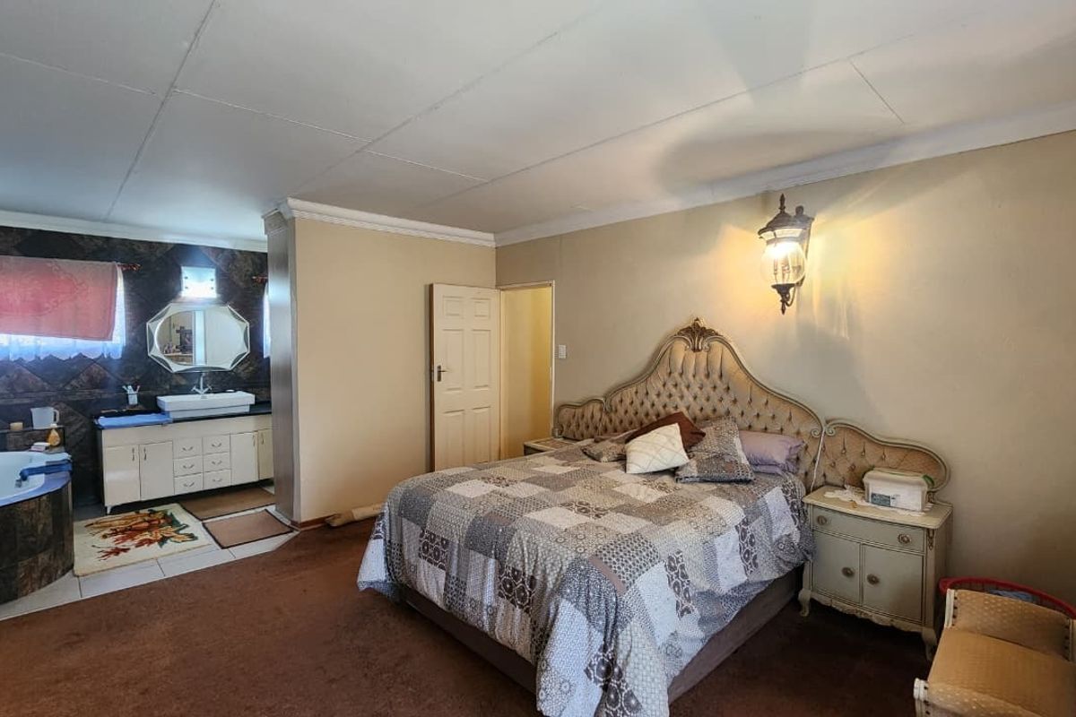 Spacious bedroom featuring an open-plan en-suite bathroom with a corner soaking tub and vanity area.