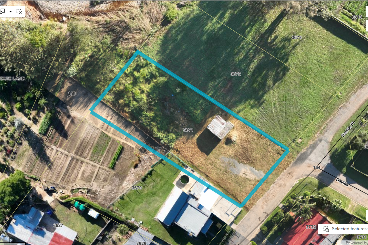 Aerial view of a vacant residential plot featuring a small shed, grassed area, and clear boundary lines.