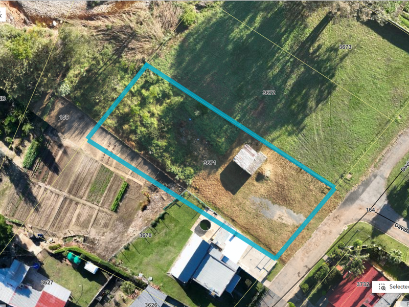 Aerial view of a vacant residential plot featuring a small shed, grassed area, and clear boundary lines.
