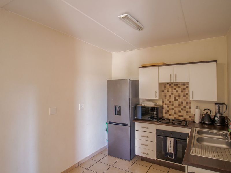 A functional kitchen featuring white cabinetry, mosaic tile backsplash, laminate countertops, and a stainless steel double sink with integrated oven and hob.