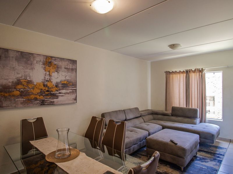 An open-plan living and dining area featuring tiled flooring and neutral wall finishes, providing a functional space for relaxation and meals.