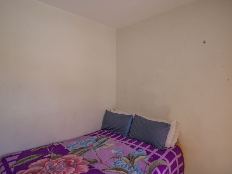 A simple bedroom space featuring plain walls and standard finishes, currently requiring minor cosmetic attention to improve its overall presentation.
