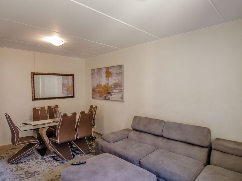 An open-plan living and dining area featuring neutral wall finishes and ceiling panels, providing a functional space for relaxation and meals.