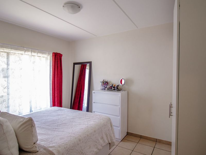 A functional bedroom featuring tiled flooring and a built-in wardrobe, offering a clean and neutral space ready for personalization.