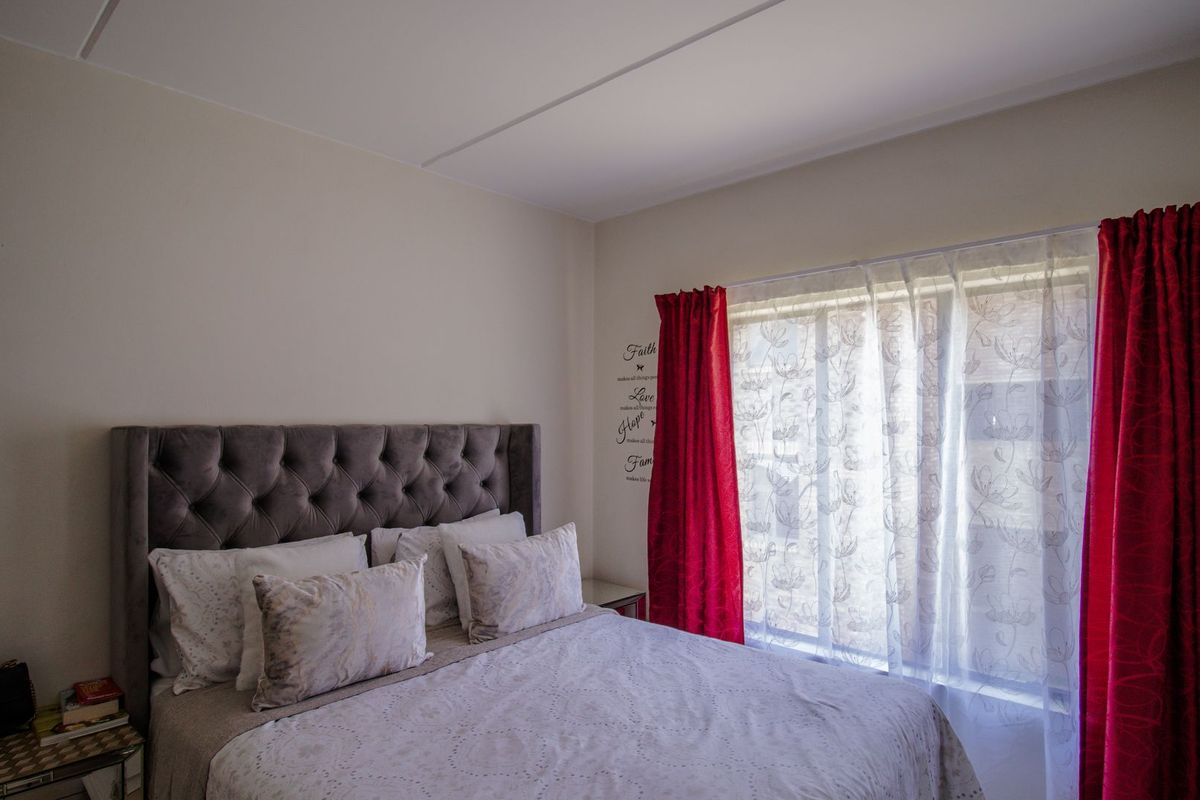 A well-lit bedroom featuring neutral walls and a large window with decorative curtains, providing a comfortable and functional living space.