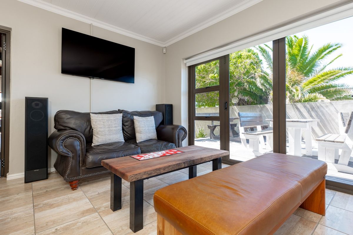 A bright living room featuring tiled flooring and large sliding glass doors that provide direct access to an outdoor patio area.