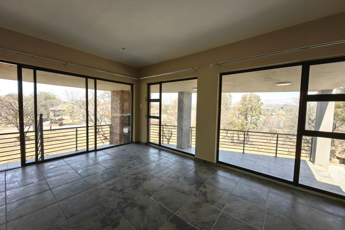 Spacious living area featuring large sliding glass doors that open onto a covered balcony with scenic views and durable tiled flooring.