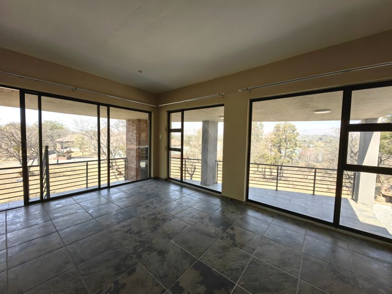 Spacious living area featuring large sliding glass doors that open onto a covered balcony with scenic views and durable tiled flooring.