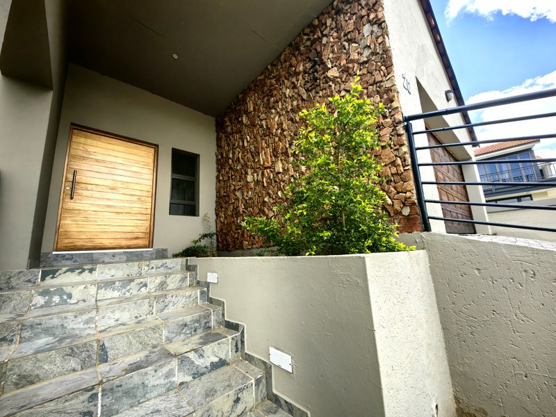Front entrance featuring a timber door, slate tiled steps, and decorative stone cladding on the exterior wall.