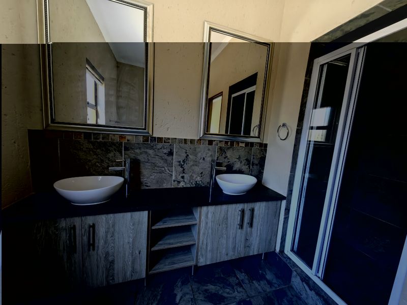 A modern bathroom featuring a double vanity with vessel sinks, stone-look splashback, and a separate shower enclosure.
