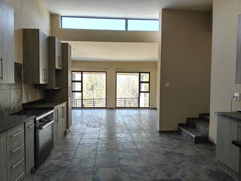 Spacious open-plan kitchen and living area featuring modern cabinetry, tiled floors, and large windows providing ample natural light and scenic views.