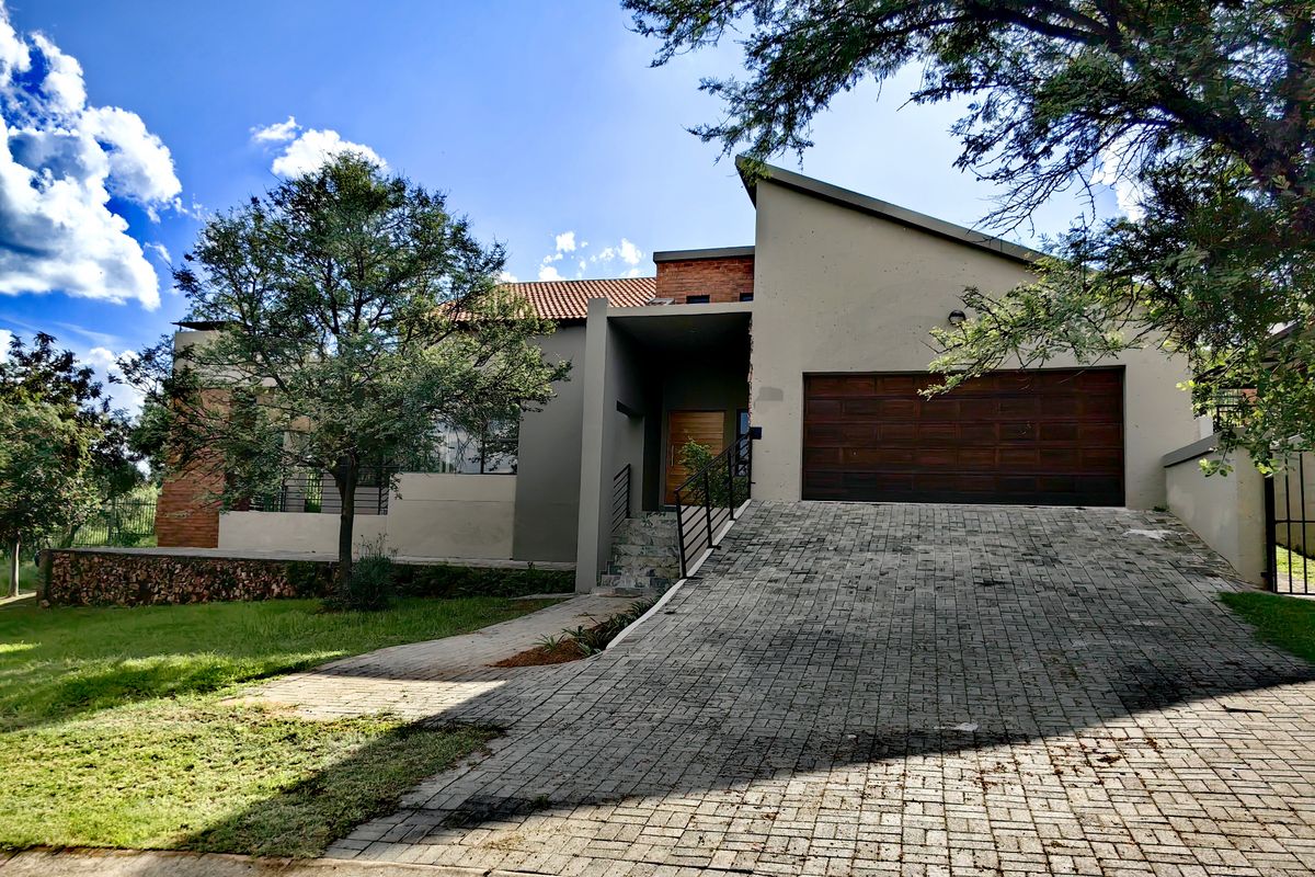 Front elevation of a modern house featuring a paved driveway, double garage, and a combination of rendered walls and stone cladding.