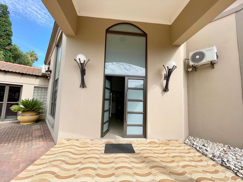 A welcoming front entrance featuring a covered porch, modern frosted glass door with arched transom, and decorative wall lighting.