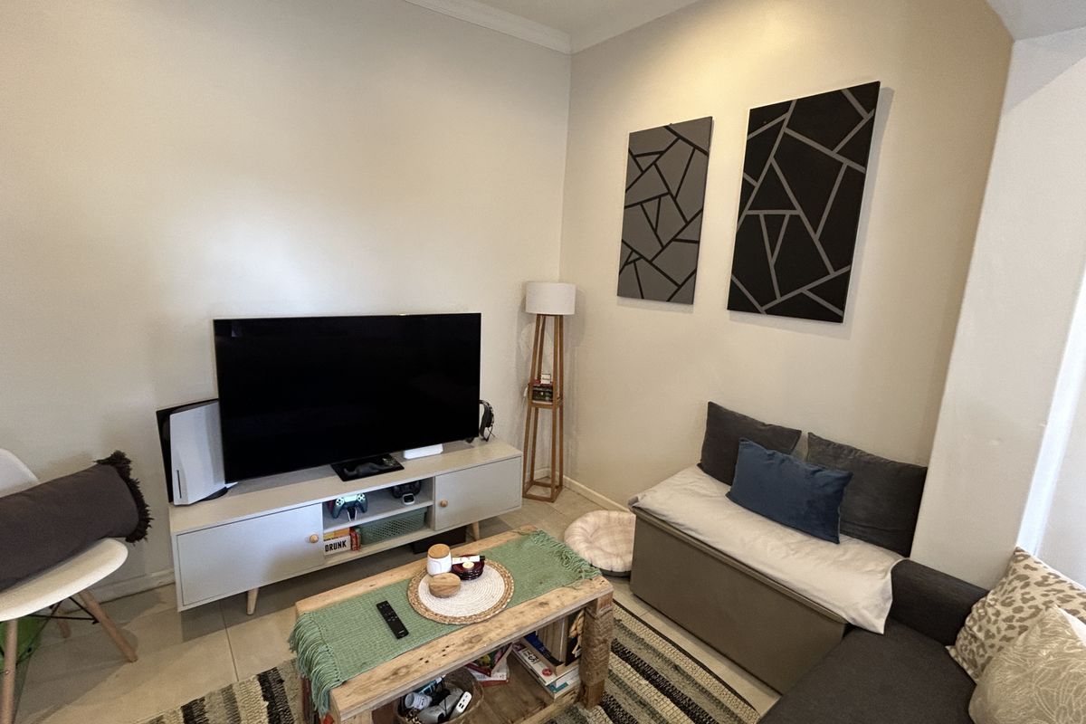 A cozy living room featuring neutral walls, tiled flooring, and decorative wall panels, providing a comfortable and functional space for relaxation.