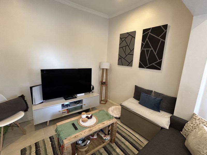 A cozy living room featuring neutral walls, tiled flooring, and decorative wall panels, providing a comfortable and functional space for relaxation.