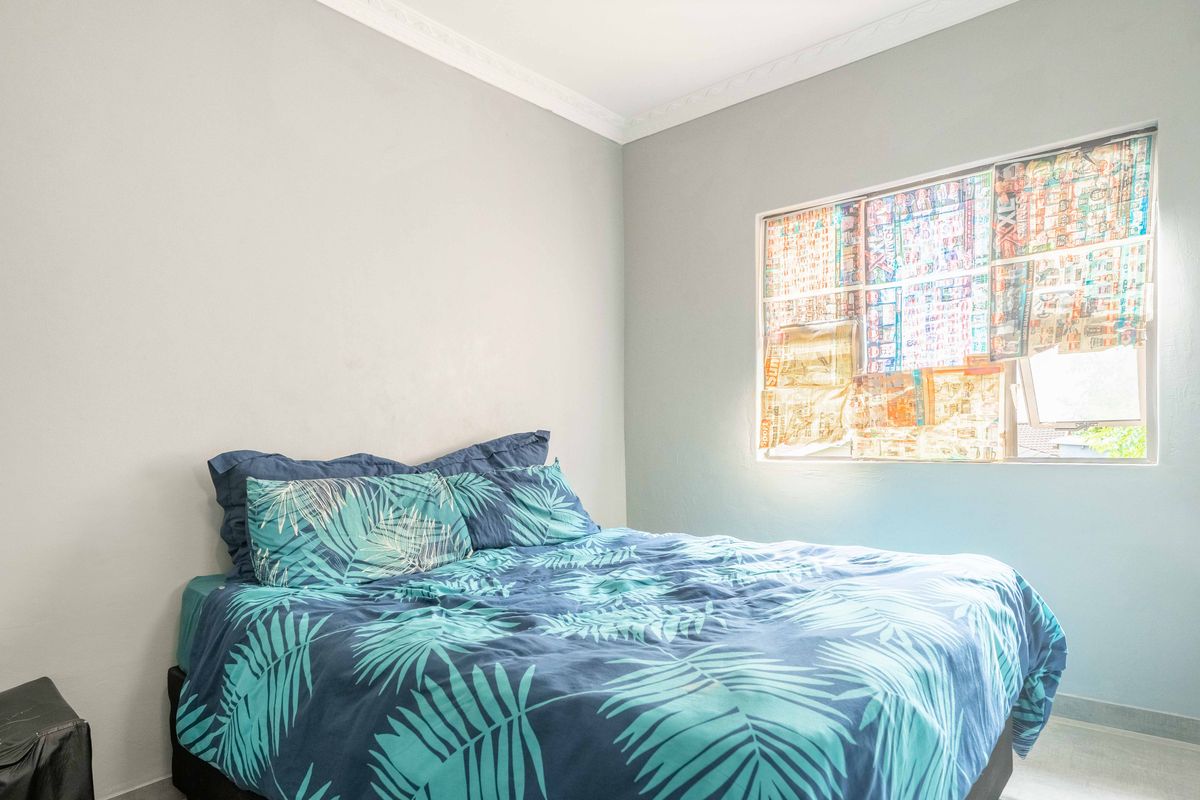 A bedroom featuring neutral walls, crown molding, and a window currently covered with paper.