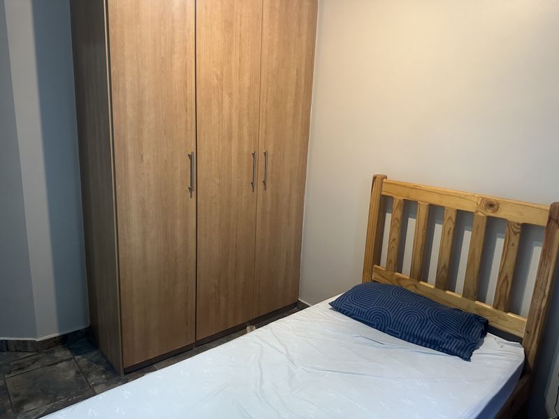 A bedroom featuring a built-in wooden wardrobe and tiled flooring.